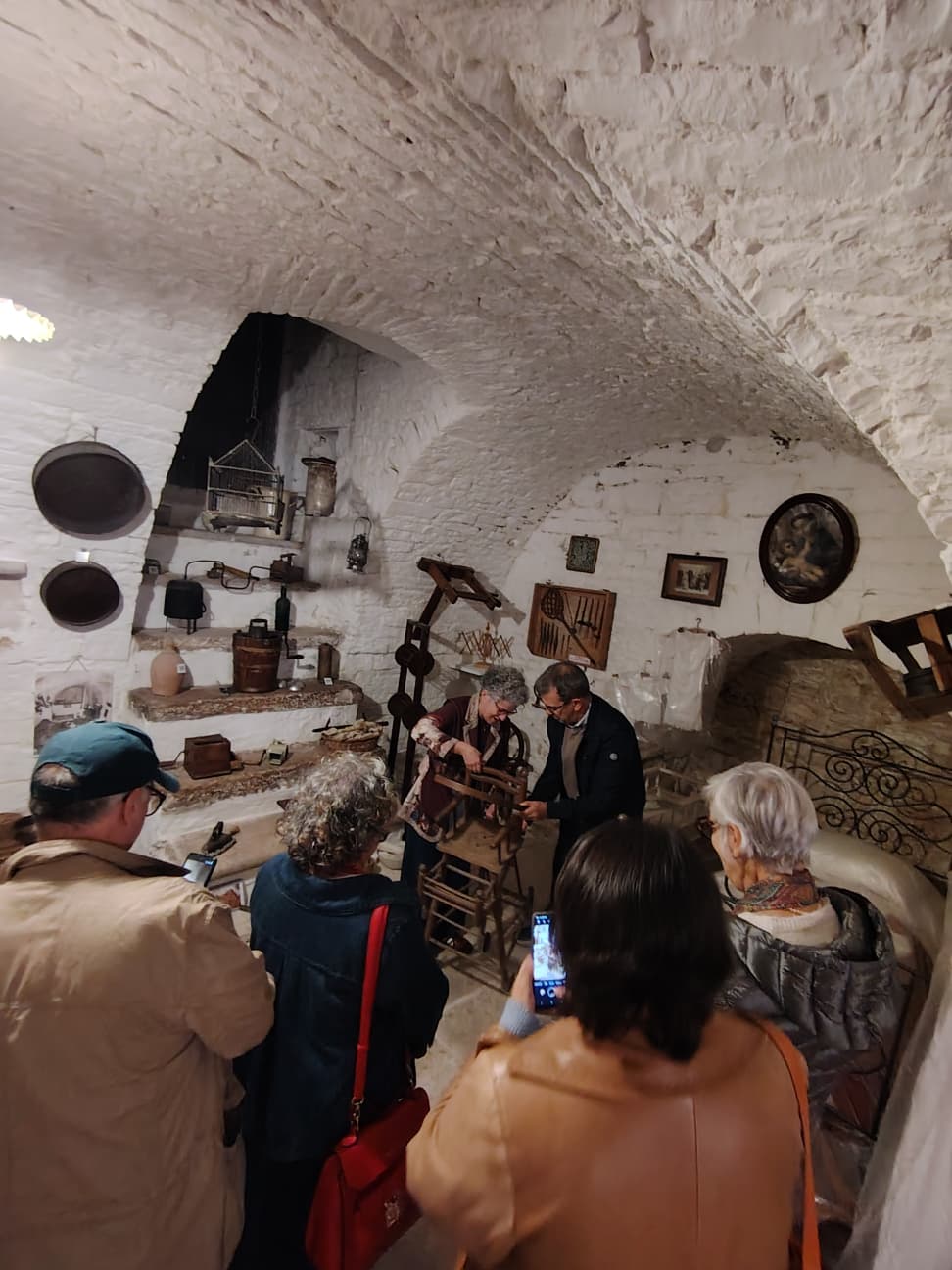 Gruppo di visitatori in un ambiente ipogeo in pietra con oggetti della tradizione locale